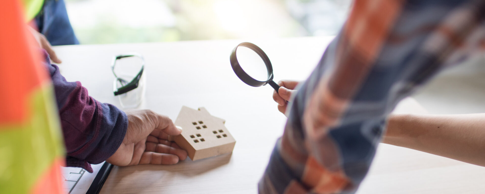 real estate and inspector concept, looking house model by magnifying glass in construction site table